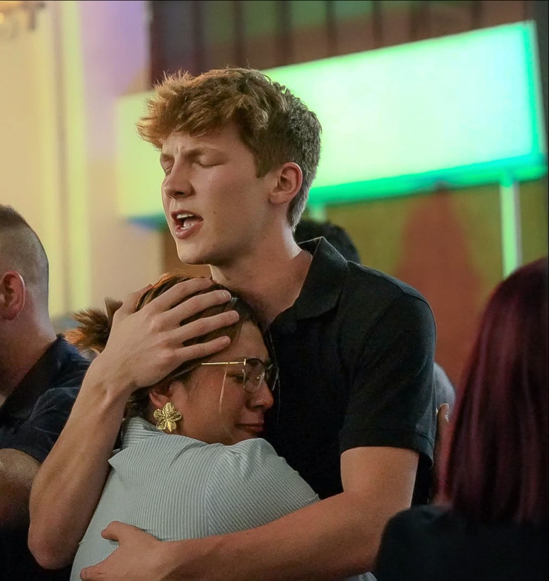 A young man embracing and comforting someone during a worship service