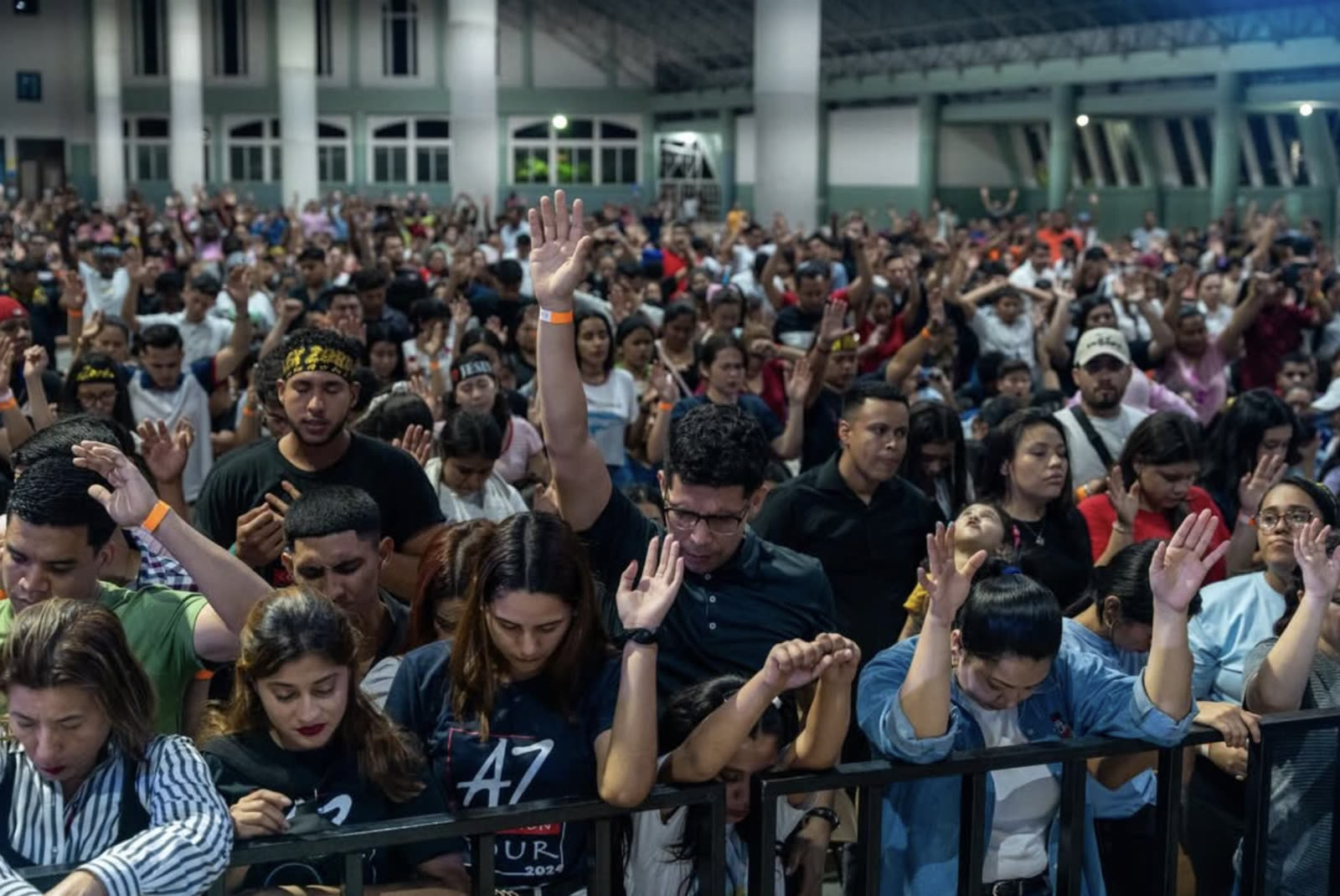 A large crowd worshiping together with hands raised
